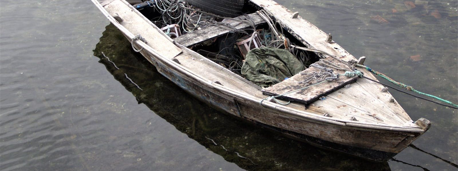 A wooden boat filled with fishing gear floats quietly in Combarro, Spain.